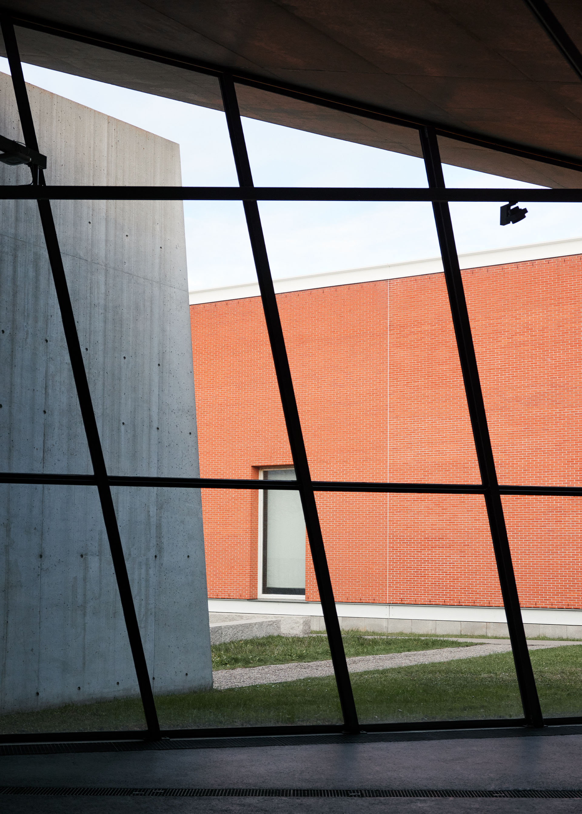 Vue d'un édifice en brique à travers une façade en verre.